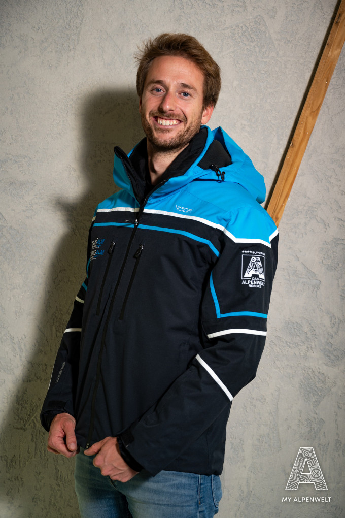 Schwarz-blaue Skijacke: Susi Alm & Hannes Alm Logo vorne rechts, Alpenwelt Logo am linken Ärmel