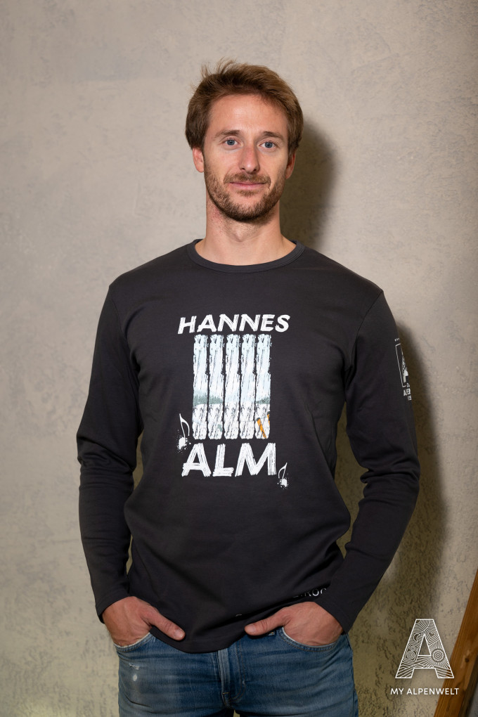 Dark gray long-sleeved shirt Front print: Hannes Alm and pattern. Print on sleeve: Alpenwelt Resort logo
