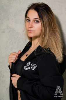 Schwarze Reißverschluss Jacke mit Kapuze. Hannes Alm und Susi Alm Logo vorne Links