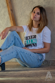 White T-shirt with the words “never calm down” and the Hannes Alm logo on the front