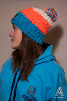Blau-orange-weiße Wollmütze mit weißem Bommel und Alpenwelt-, Susi Alm und Hannes Alm Logo Patch